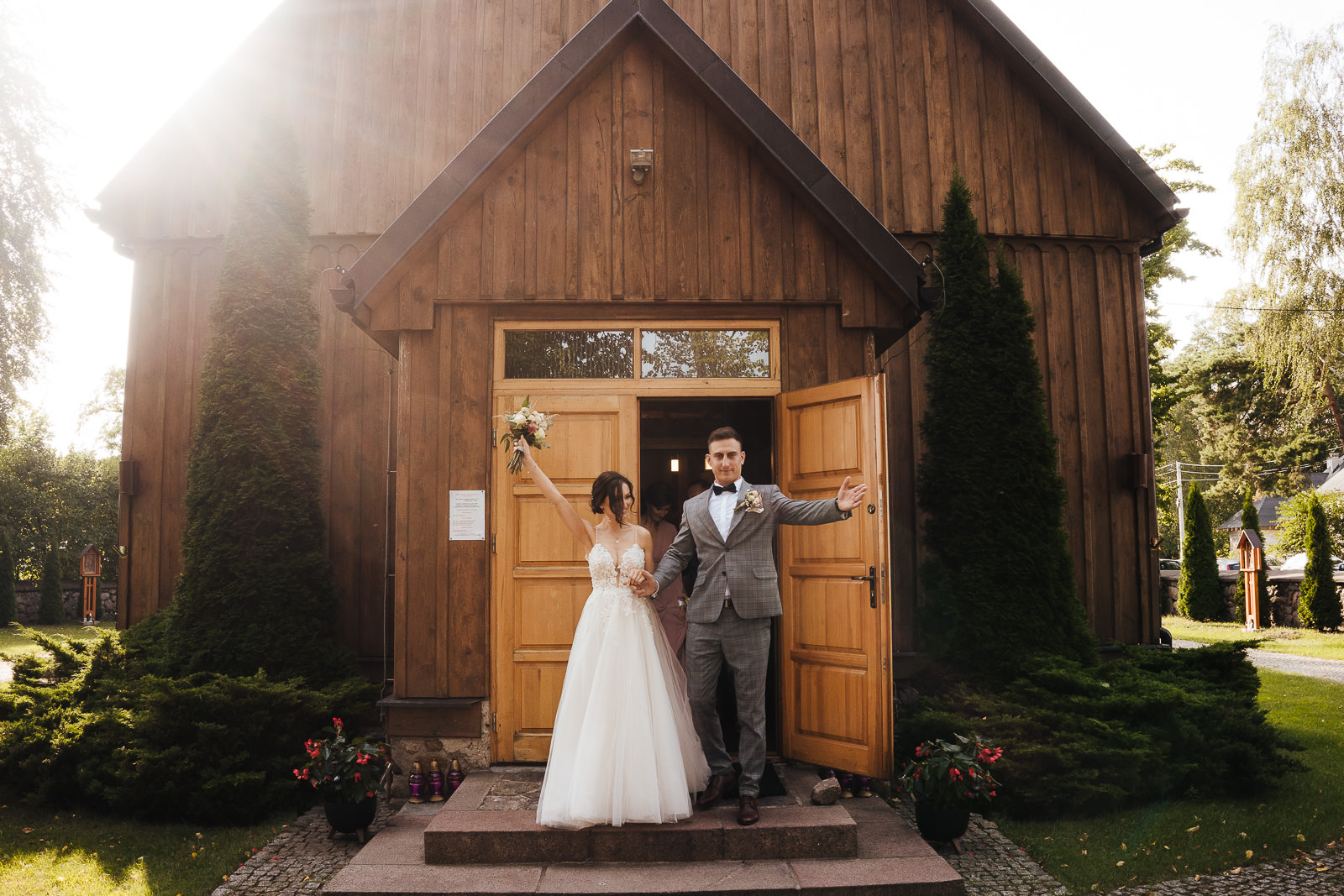 wyjście pary młodej z drewnianego kościoła hacienda barnhouse fotograf na ślub Piotr Czyzewski